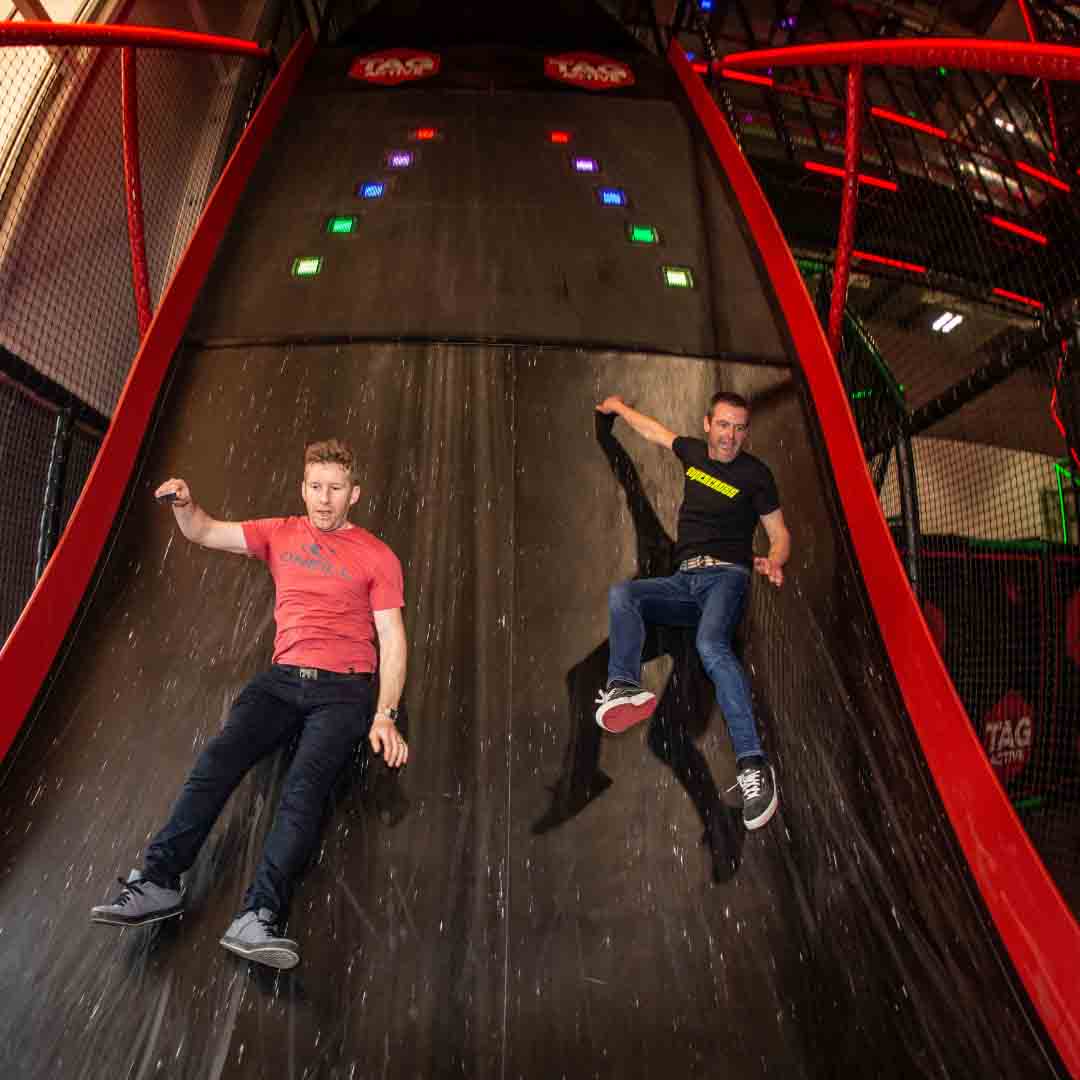 boys sliding down obstacle wall