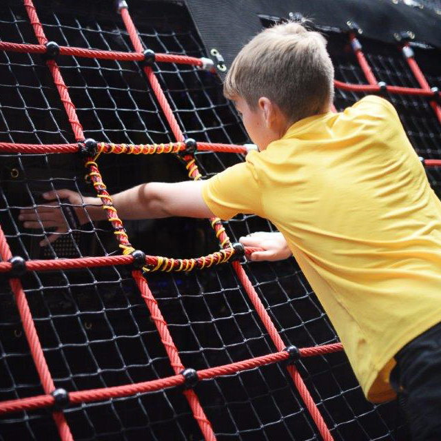 boy climbing obstacle wall